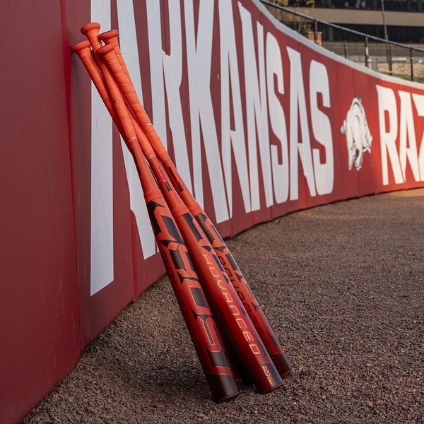 2026 Easton Ghost® Advanced Fastpitch Bats leaning against the fence at the University of Arkansas