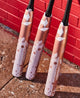 2025 DeMarini Whisper -9 Fastpitch Bats leaning against a dugout wall