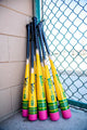 Several Victus Vibe Pencil Baseball Bats stacked by the dugout fence