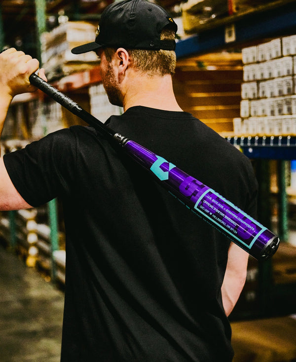 Man carrying the 2026 DeMarini The Goods™ Royal Purple -3 BBCOR Baseball Bat through the DeMarini warehouse