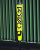 2026 DeMarini Omega™ Electric Yellow -3 BBCOR Baseball Bat resting against a metal fence