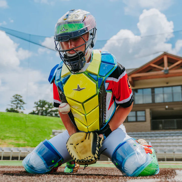 Young catcher blocking a low pitch while wearing the All Star MVP-Pro Series™ Youth Catching Kit