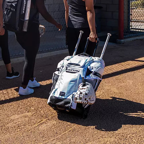 Fastpitch player rolling the Easton Jen Schro Catcher's Wheeled Bag towards the field