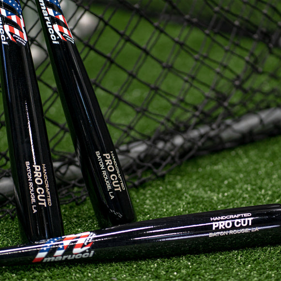 Three Marucci USA Professional Cut Wood Bats beside a batting cage