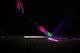 Player tapping the  barrel of the 2027 Easton Hype Fire USSSA Baseball Bat on a turf surface in the dark with neon lights radiating from the ground