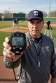 Coach demonstrating the Ultrak 435 Pitch Counter with Strike Pct./Pitch Speed Monitor - 10 Memory Stopwatch