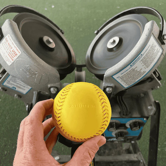 Person feeding a Truflight Aceballz Pitching Machine Softball into a pitching machine