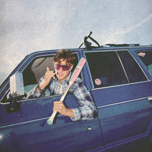 Player leaning out the window of a car holding the 2026 Combat MFG Spec H1 Hybrid Coastal Collective Uluwatu -3 BBCOR Baseball Bat and flashing the shaka sign