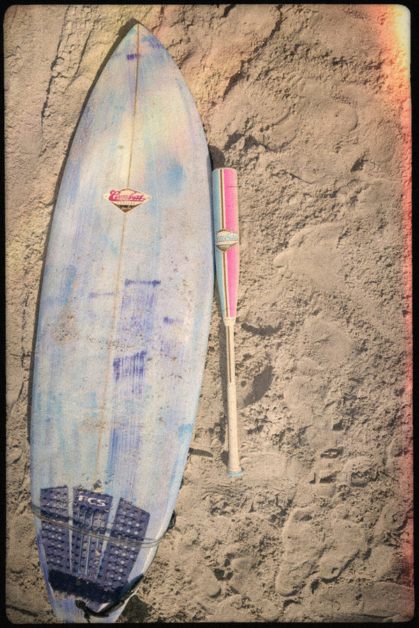 2026 Combat MFG Spec H1 Hybrid Coastal Collective Uluwatu -3 BBCOR Baseball Bat laying on the sand near a surfboard