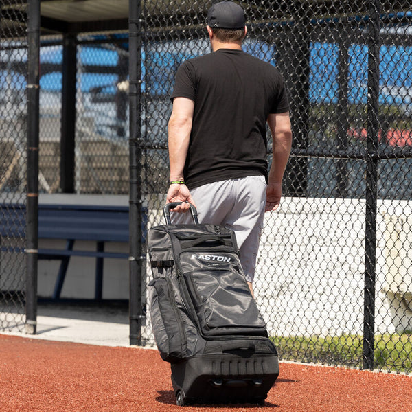 Player wheeling the Easton Wheelhouse Pro Wheeled Bag into the dugout