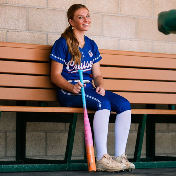 Player in the dugout modeling the 2025 Easton Ghost OG Rainbow Sherbert Fastpitch Bat
