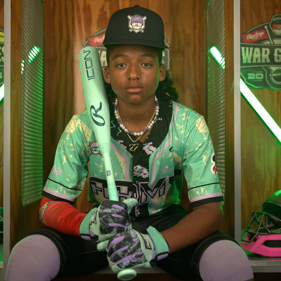 Young player sitting in a locker holding the 2026 Rawlings ICON™ USSSA Baseball Bat