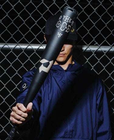 Player holding a 2025 Demarini The Goods™ One Piece -3 BBCOR Baseball Bat