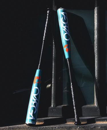 2026 DeMarini Omega -3 BBCOR Baseball Bats leaning against a wall