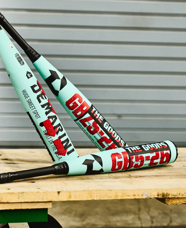 Three 2026 DeMarini The Goods™ USSSA Baseball Bats resting on a cart