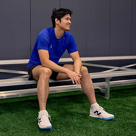 Shohei Ohtani resting on a bench while wearing the New Balance Ohtani 1 Lab Work Training Shoe